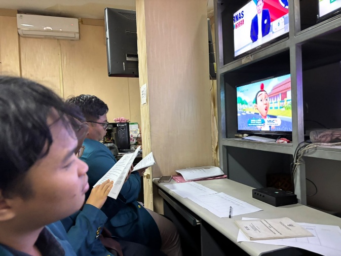 A group of people sitting at a desk looking at a television AI-generated content may be incorrect.
